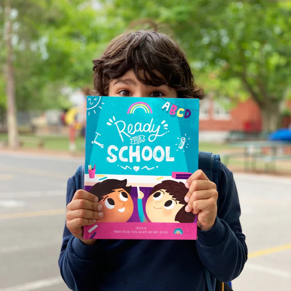 Child holding book titled 'Ready for School'