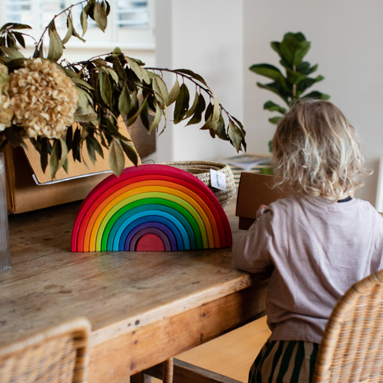 Child playing with rainbow block toy on wooden table