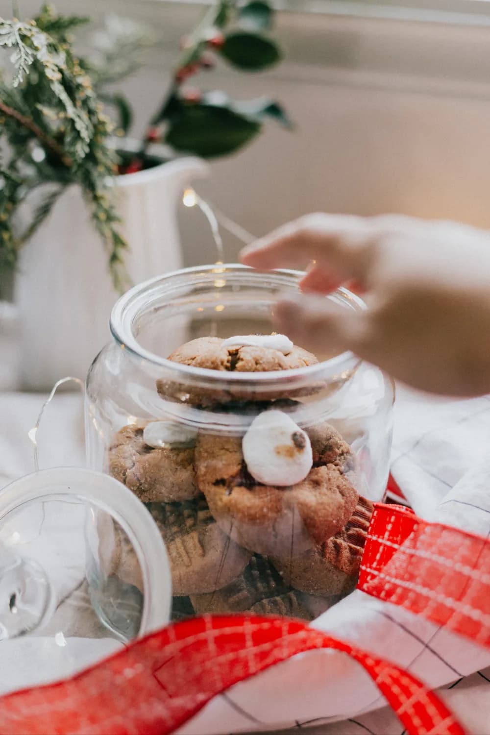 a glass jar of cookies on a table with a gift and a gift box on top