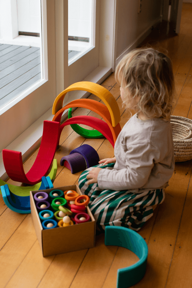 child playing with wooden rianbow