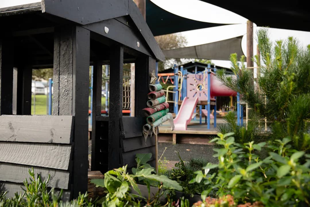 Wooden play house with playground in background