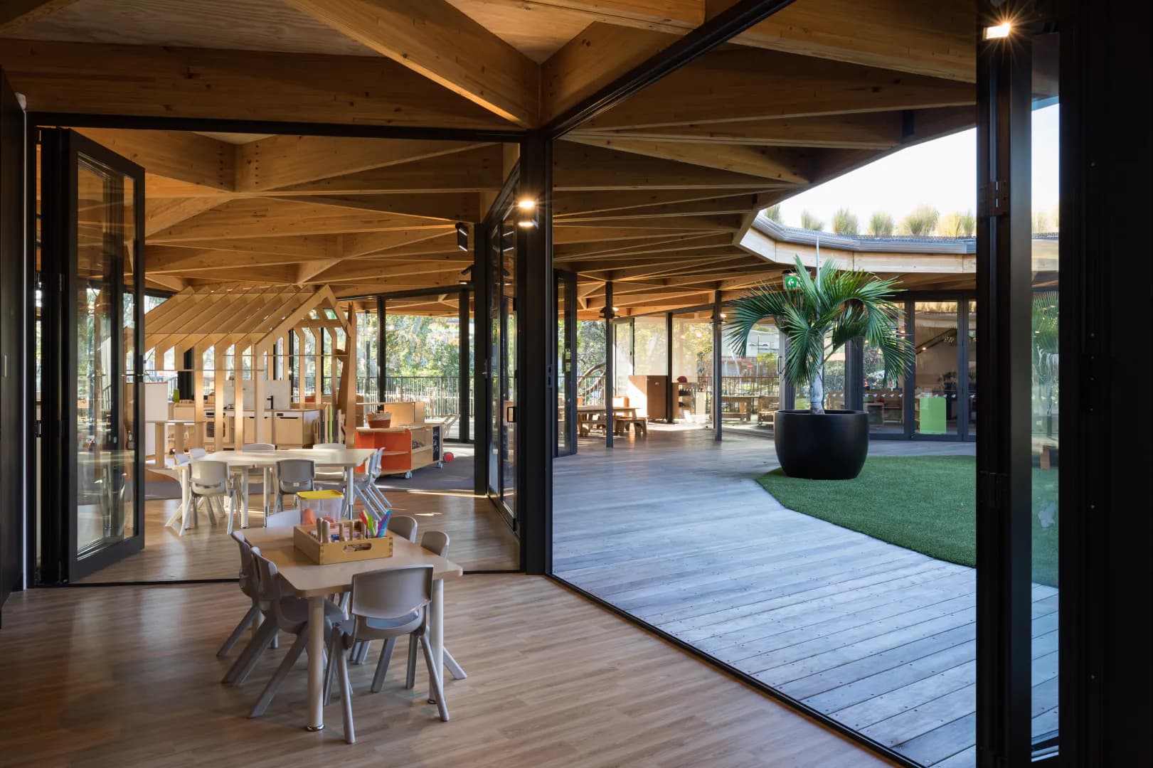 Interior of Kakapo Creek with a wooden table opening out in a green central playarea