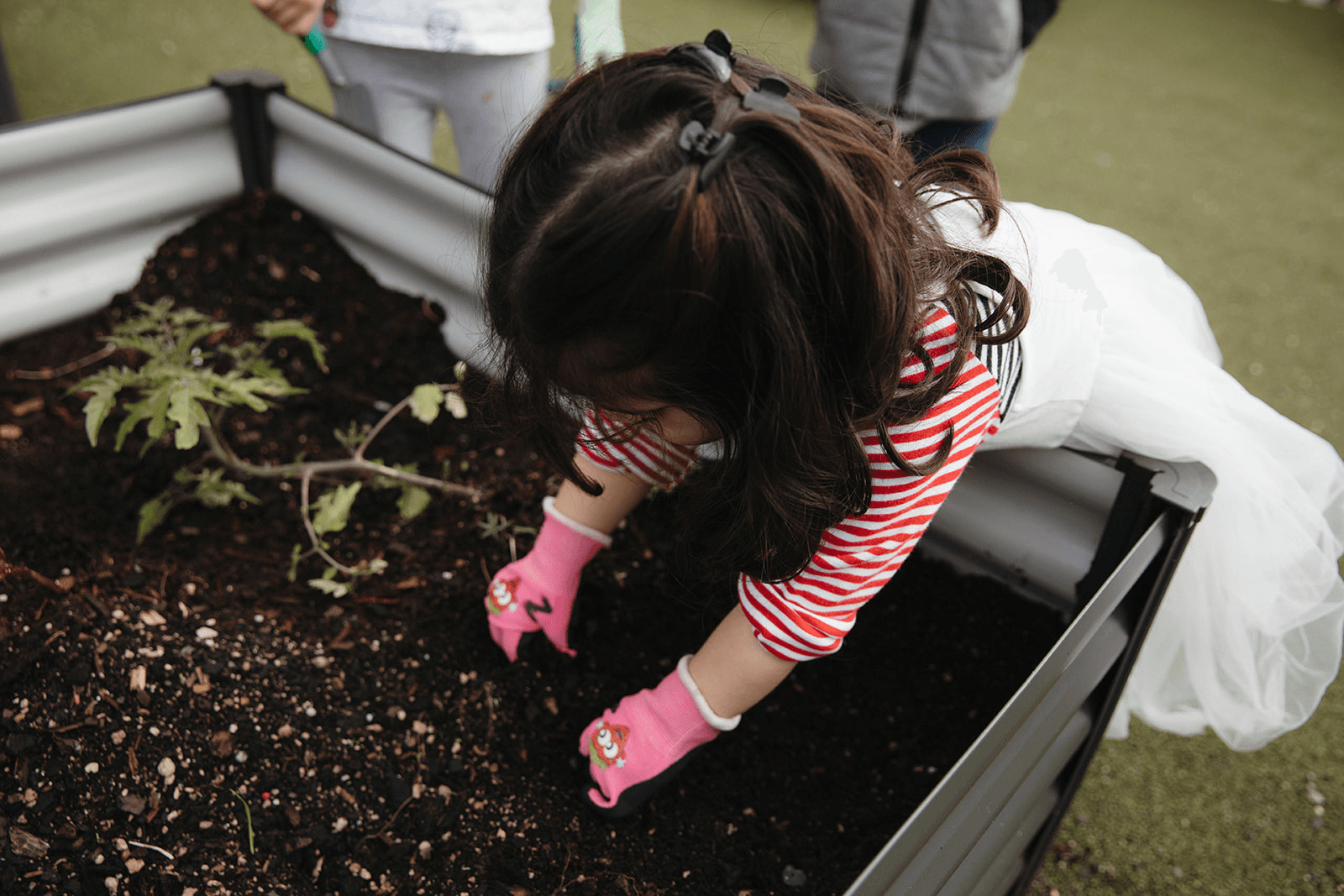 Young child gardening with gloves