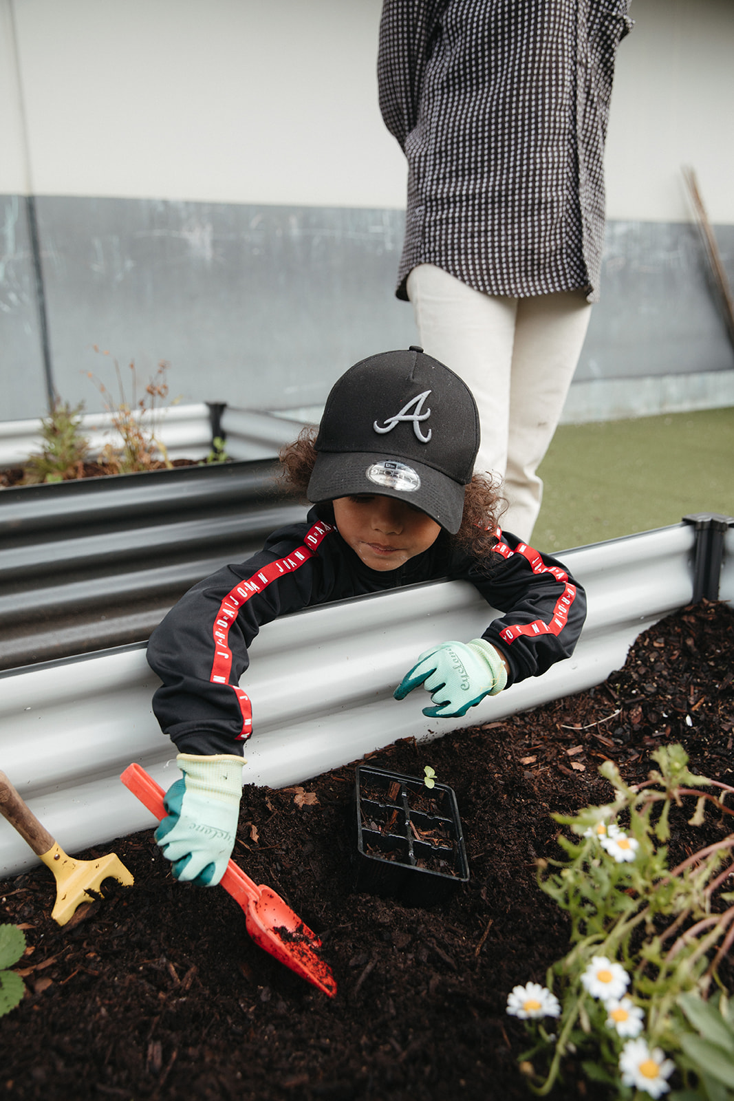 Young child gardening with red spade
