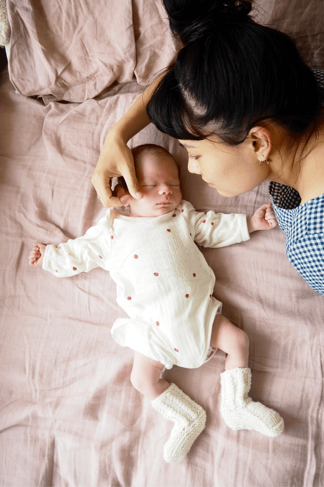 Mother and baby lying on bed